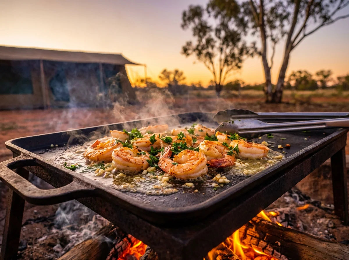 Garlic butter prawns sizzling on a cast iron camp hotplate over a campfire in the Australian bush at golden hour
