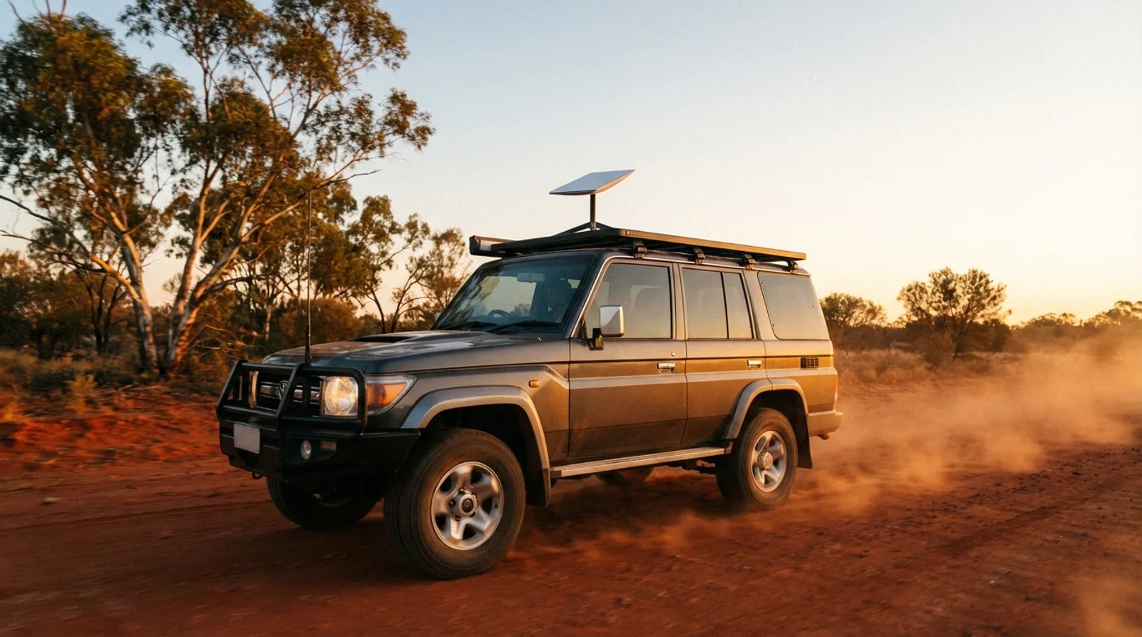 Starlink Mini securely mounted on the roof rack of a 4WD travelling along a red dirt outback Australian road at golden hour