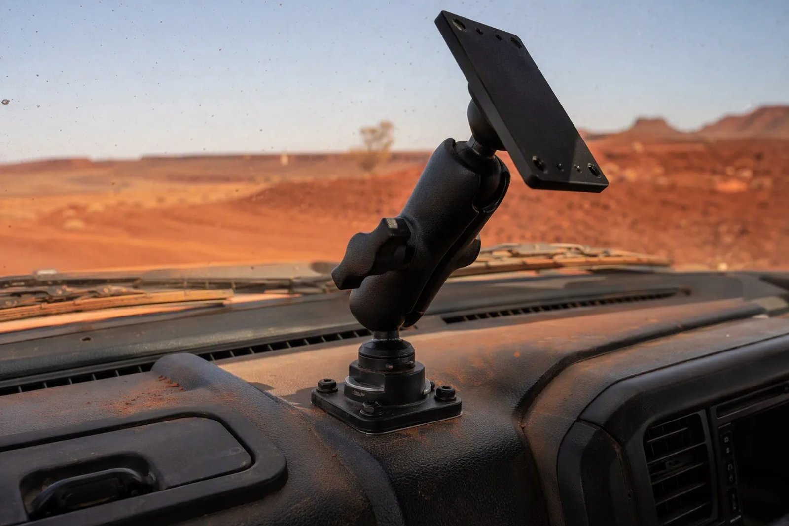 A close-up of a heavy-duty 1.5-inch ball Double Socket Arm mount for Starlink Mini installed on a rugged truck dashboard in a dusty outback environment.