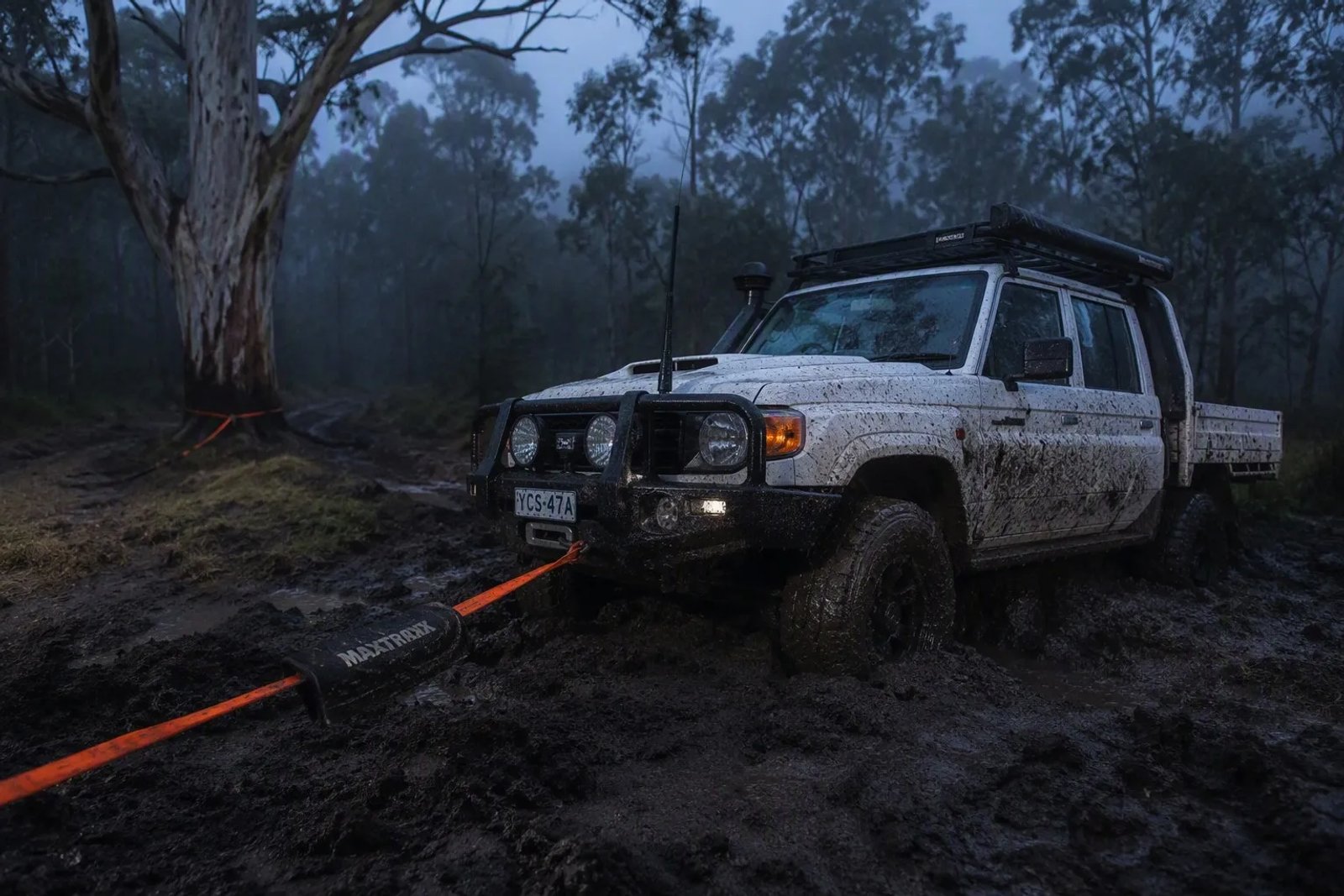 Solo 4WD recovery in deep winter mud with a Toyota 79 Series, synthetic winch line, and proper damper on a remote Australian bush track.