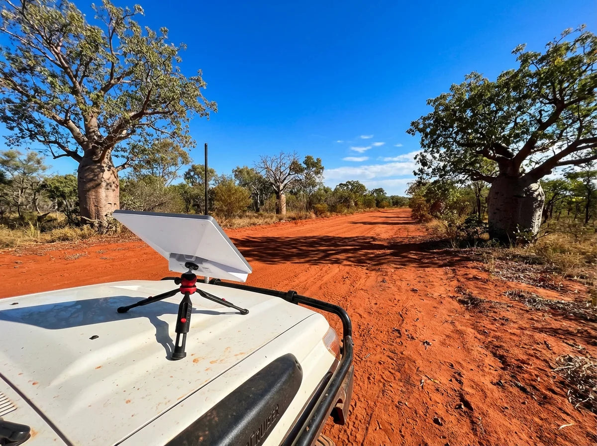 Starlink Mini with PeakDo battery on tripod on LandCruiser bonnet on red dirt track in the Kimberley with boab trees