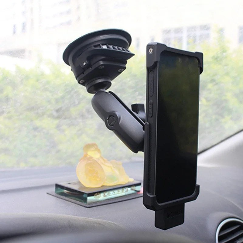 Installed lifestyle shot: twist-lock suction cup mount holding a phone in a cradle, attached to a car windscreen on the interior side